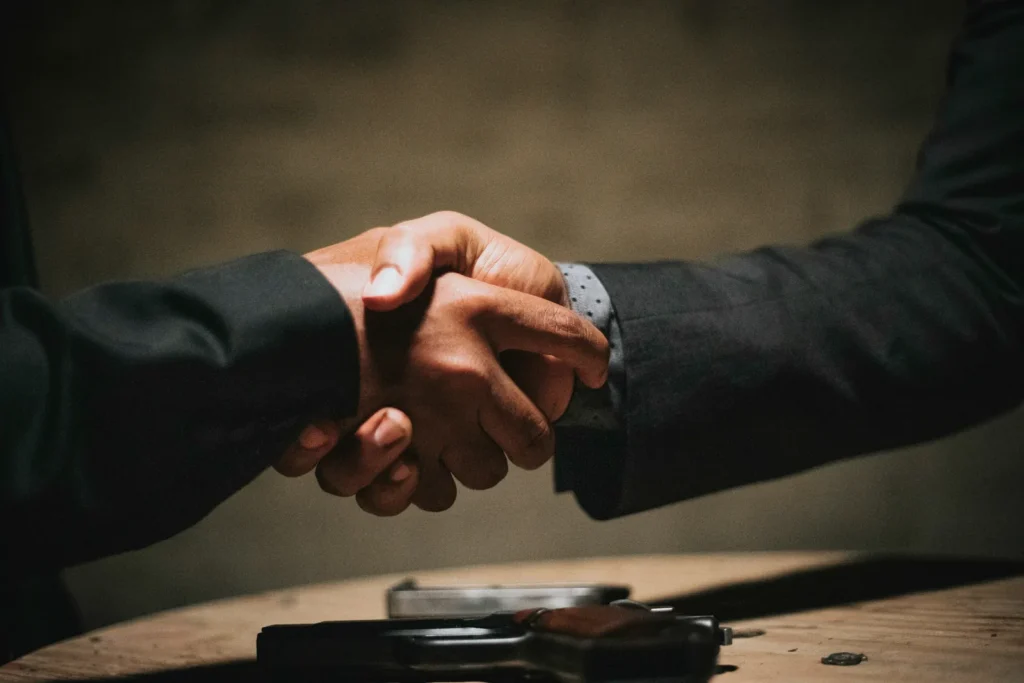 Two people shaking hands over a wooden table
